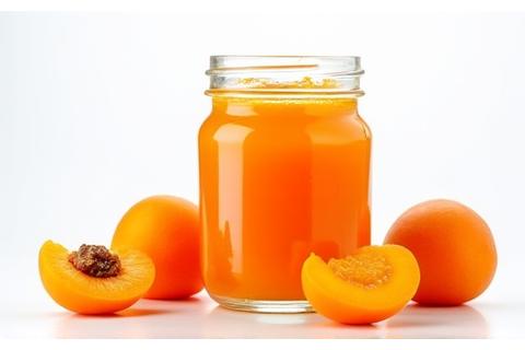 Glas mit leuchtend oranger Marillenkonfitüre.